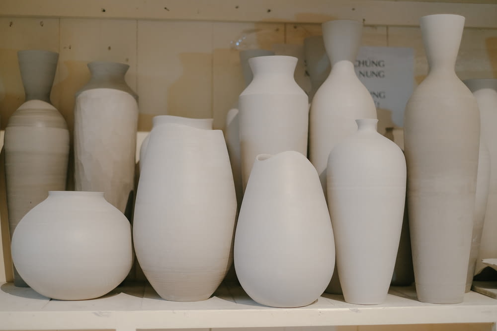 a bunch of white vases sitting on a shelf