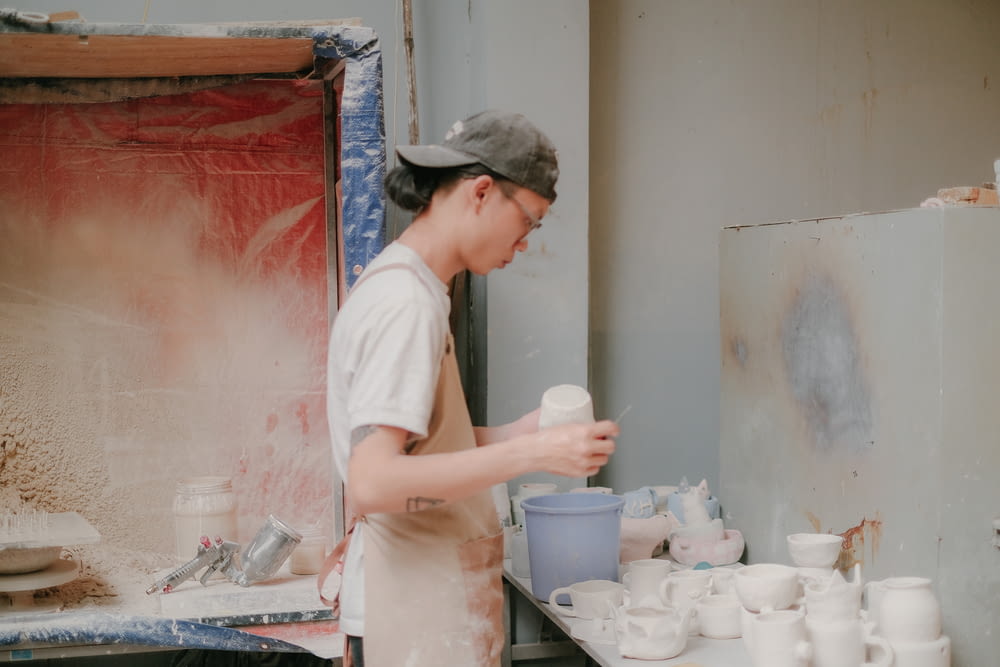 a woman in a white shirt is making cups