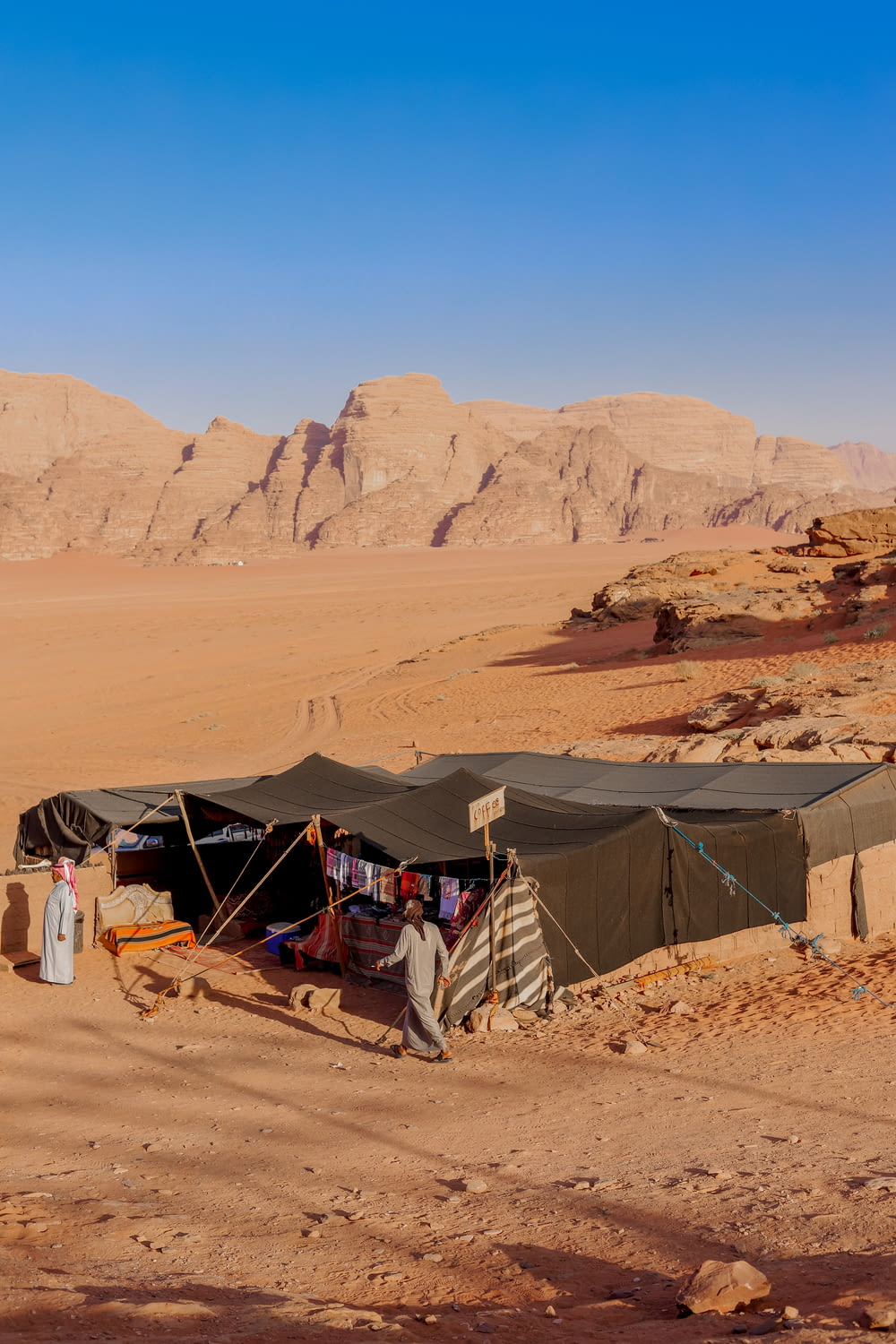 a tent in the middle of a desert with mountains in the background
