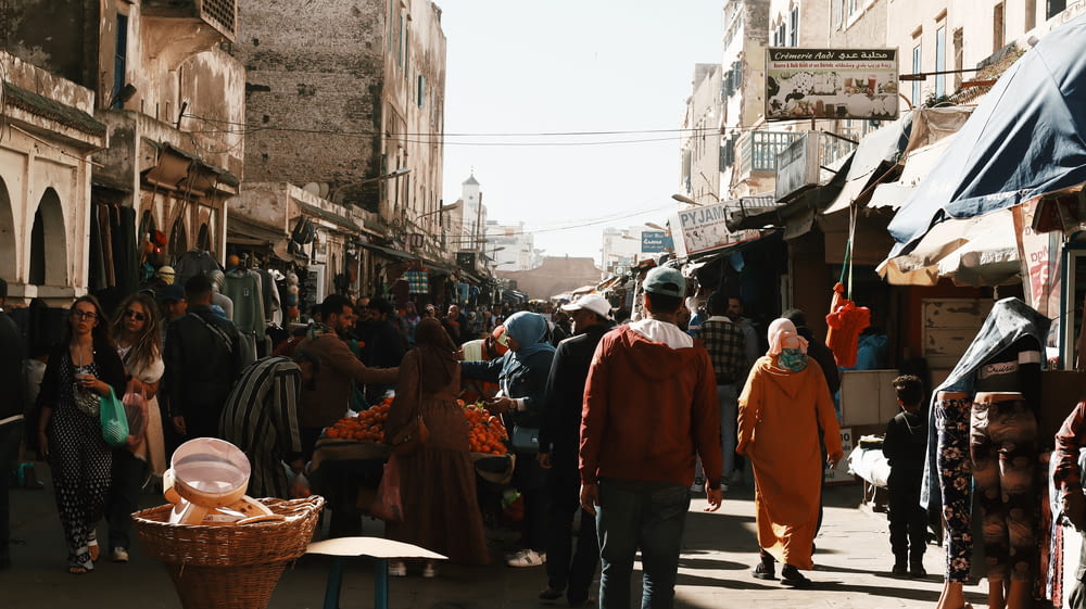 a group of people walking down a street next to a market