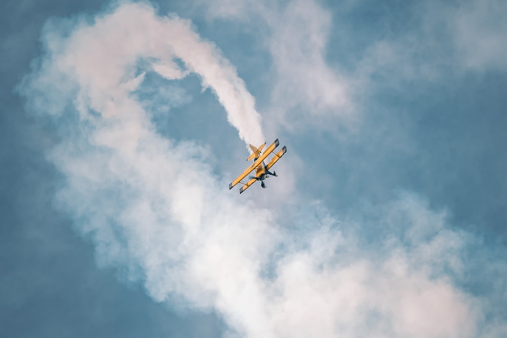 a small plane flying through a cloudy blue sky