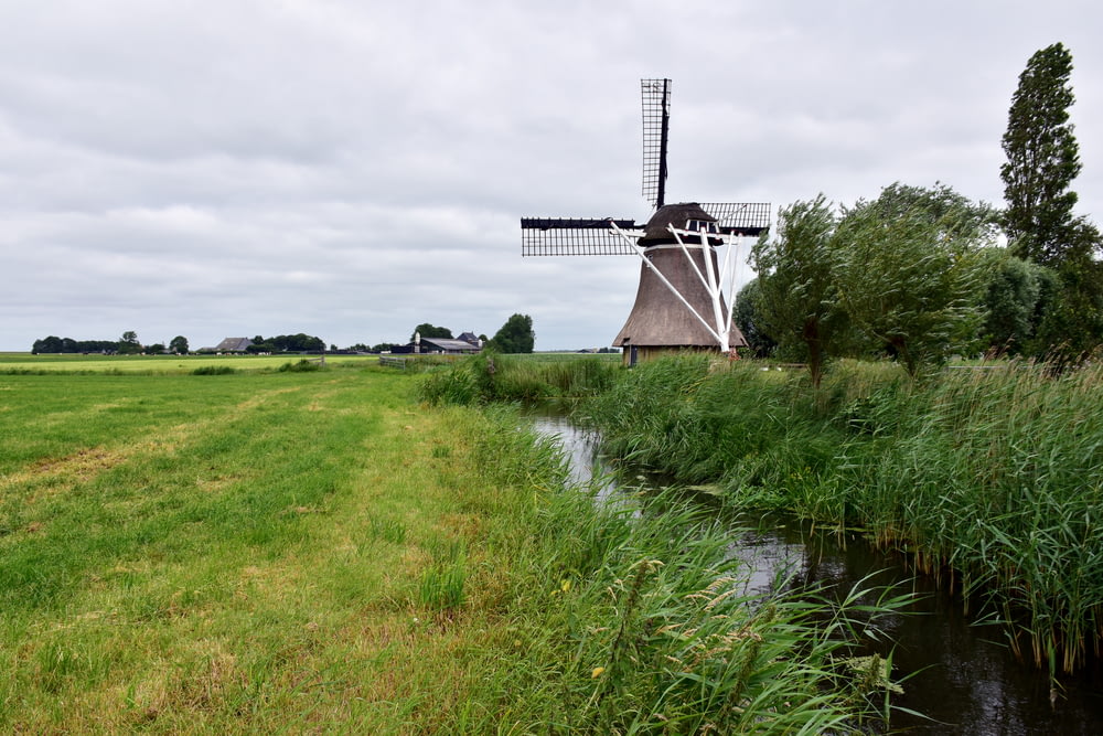 um moinho de vento em um campo ao lado de um rio