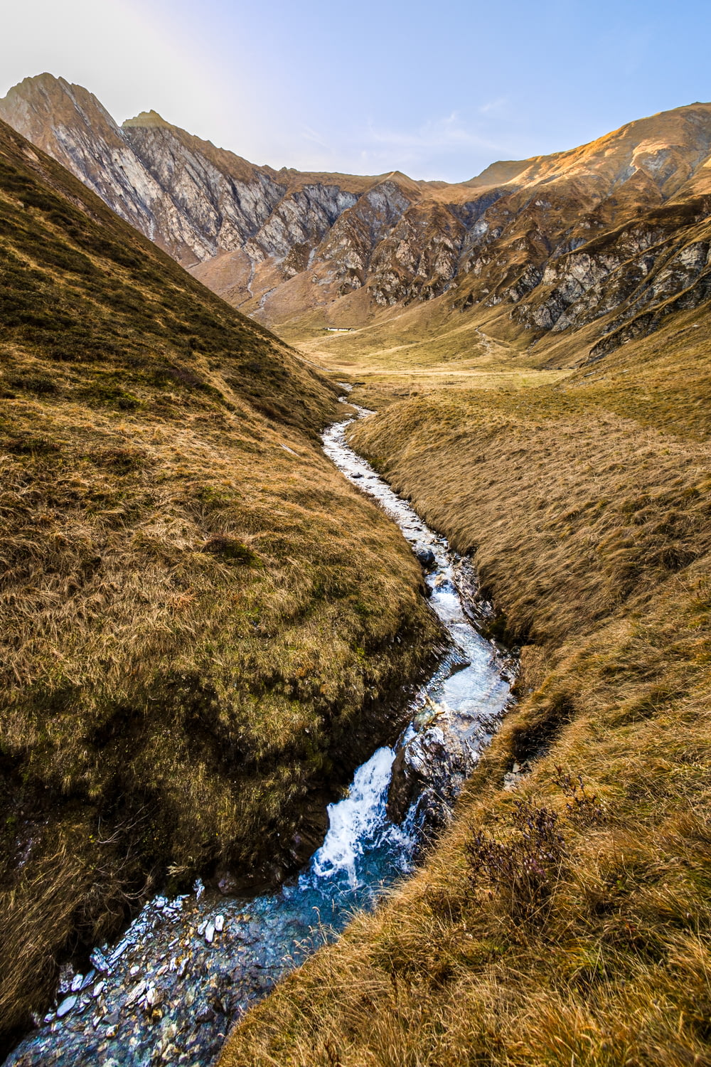 a stream running through a grass covered valley