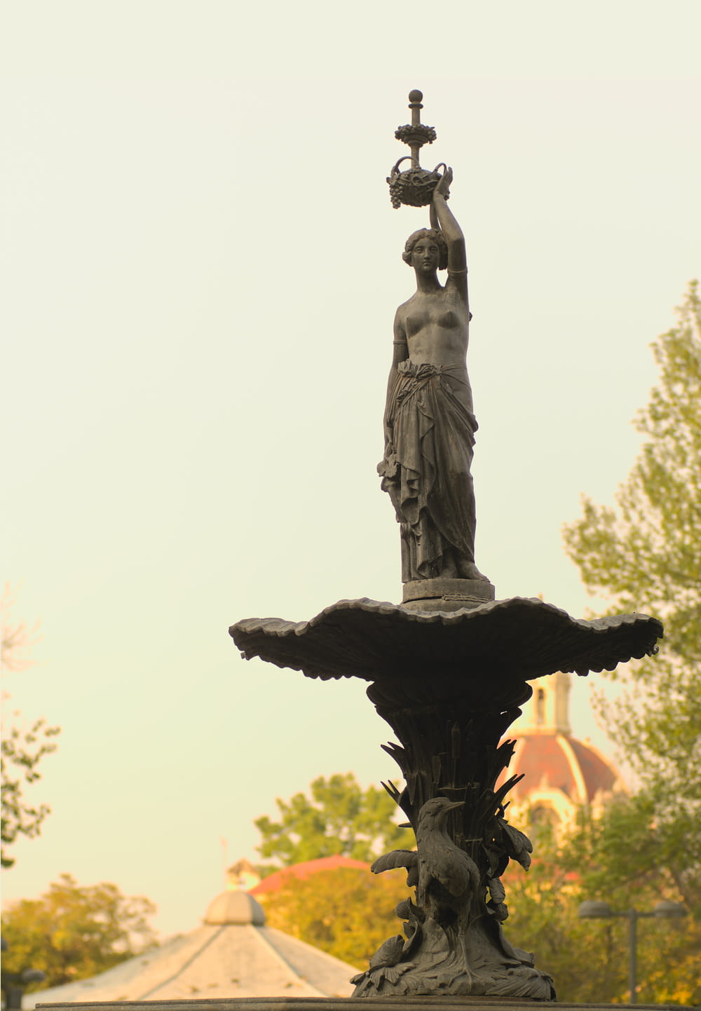 a statue of a woman holding a lamp on top of a fountain