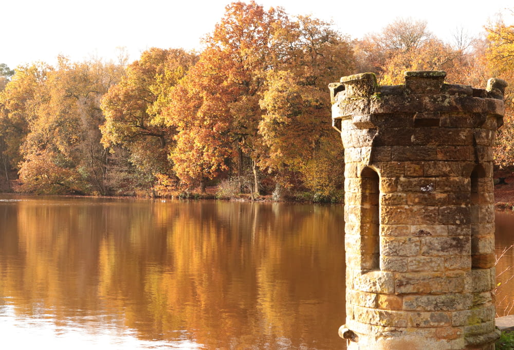 a brick tower sitting on top of a lake surrounded by trees
