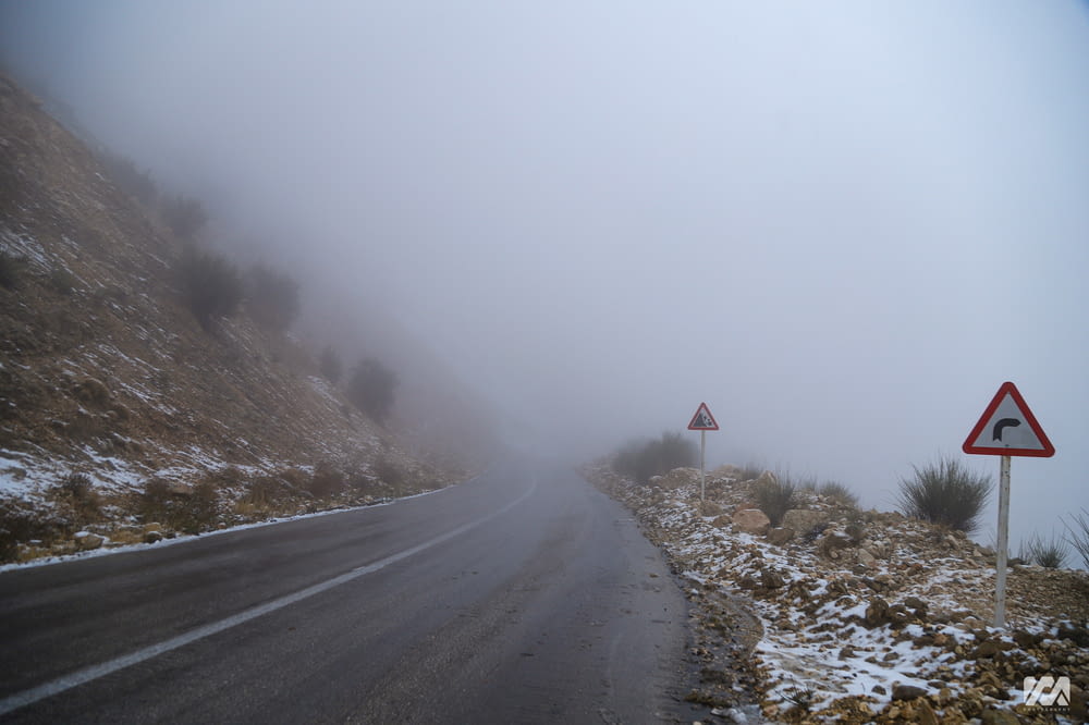 a foggy mountain road with a red and white sign