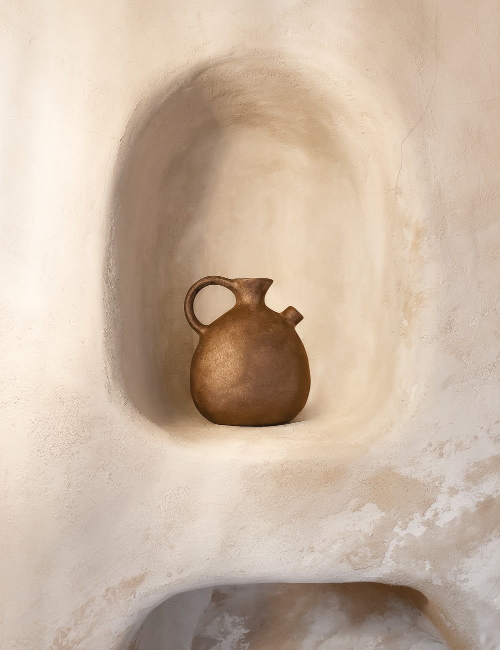 a brown vase sitting on top of a white wall