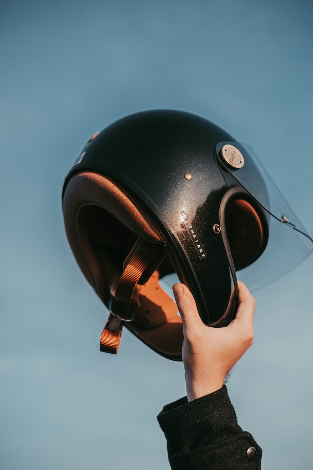 a person is holding a helmet up to the sky