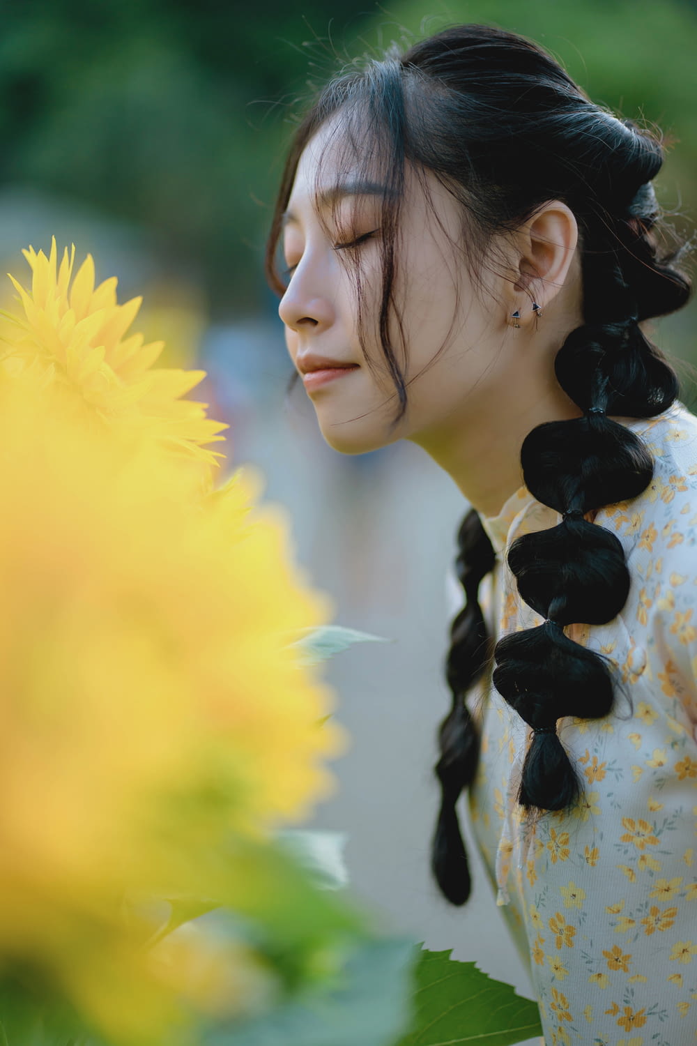 a woman with long black hair standing next to a yellow flower