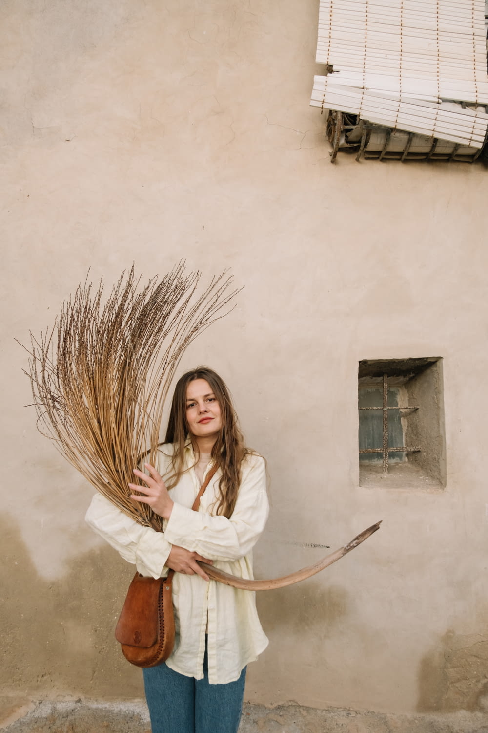 a woman holding a large bundle of dried plants