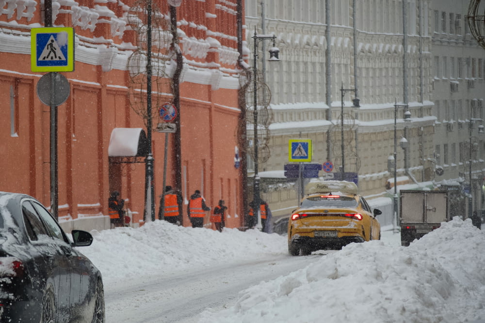 a yellow taxi driving down a snow covered street