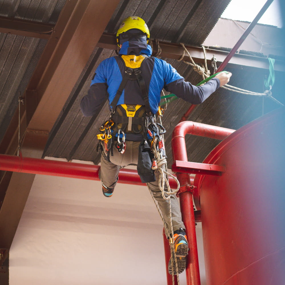 a man in safety gear climbing up a red railing
