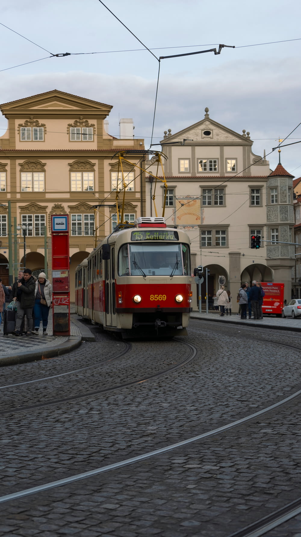 a red and white train traveling down a street next to tall buildings