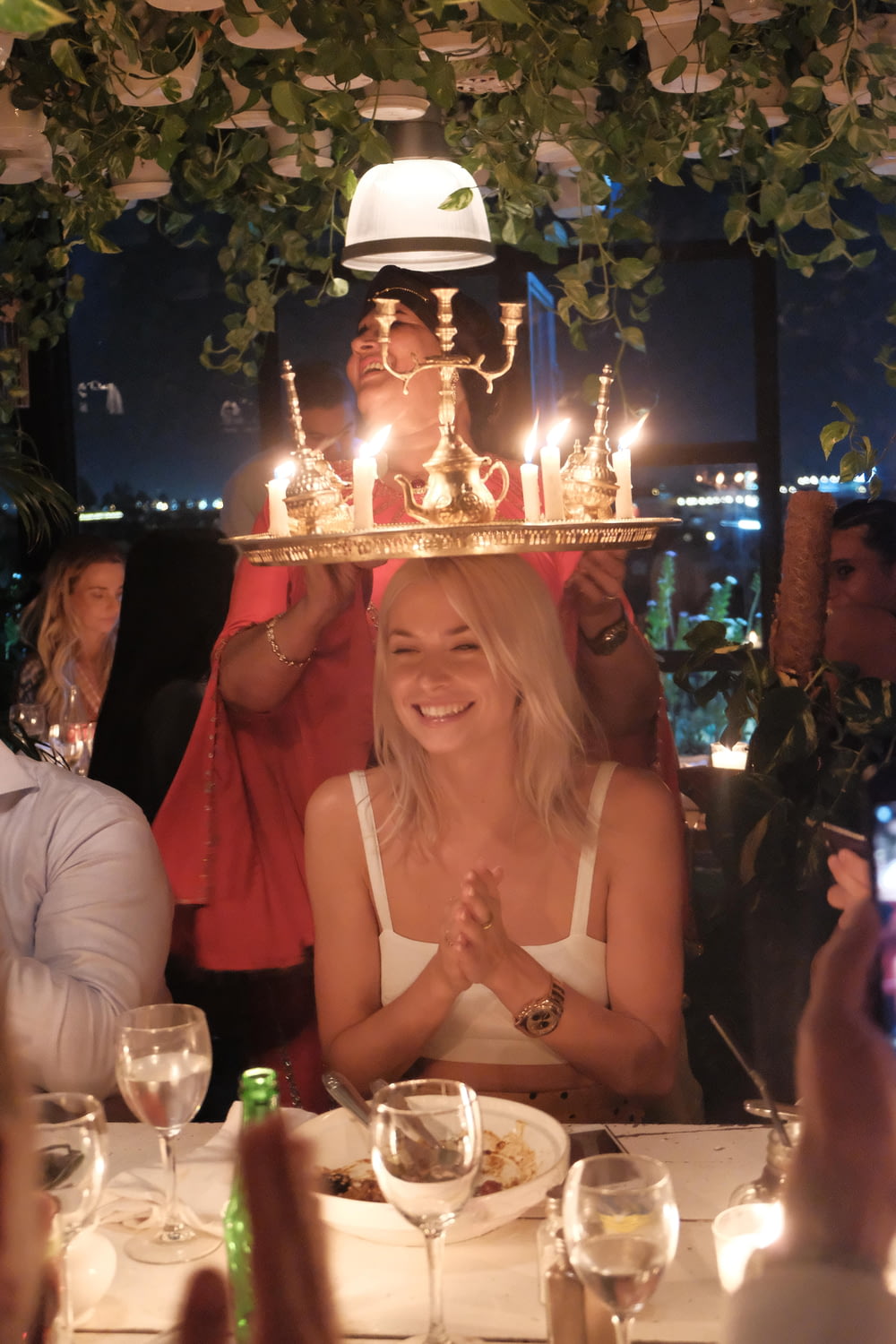 a woman sitting at a table with a cake on top of her head