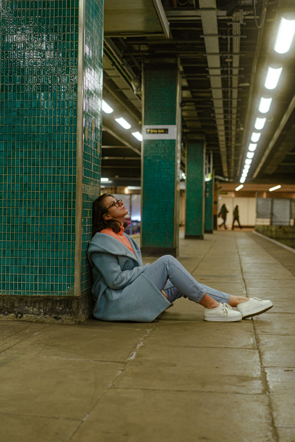 a woman sitting on the ground in a subway station