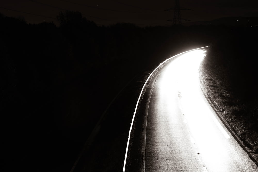 a black and white photo of a road at night