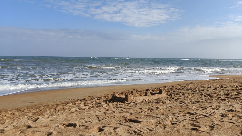 a sandy beach next to the ocean under a blue sky