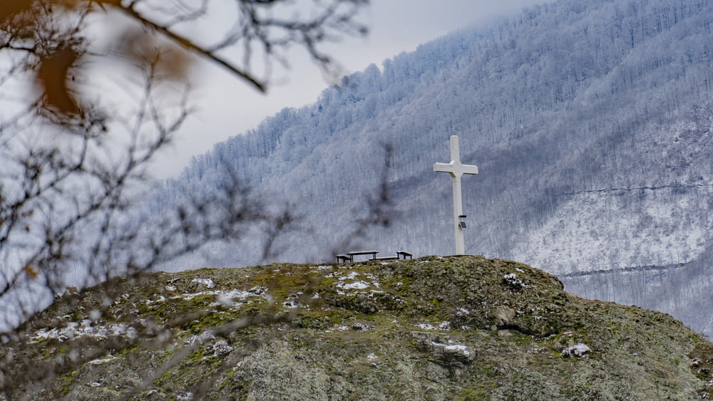 a cross on top of a hill with a mountain in the background