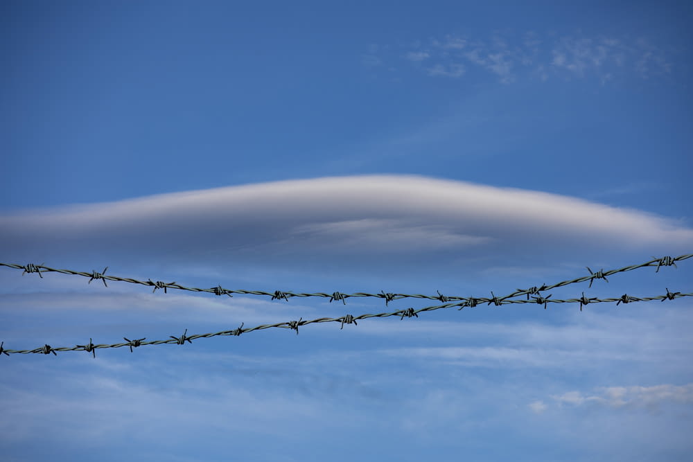 a large cloud looms over a barbed wire fence