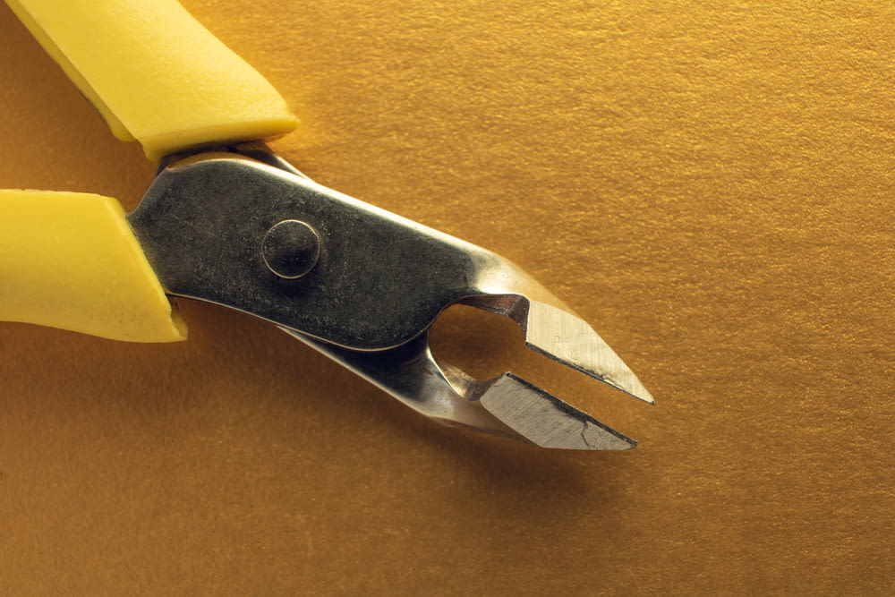 a pair of pliers cutting a piece of yellow paper