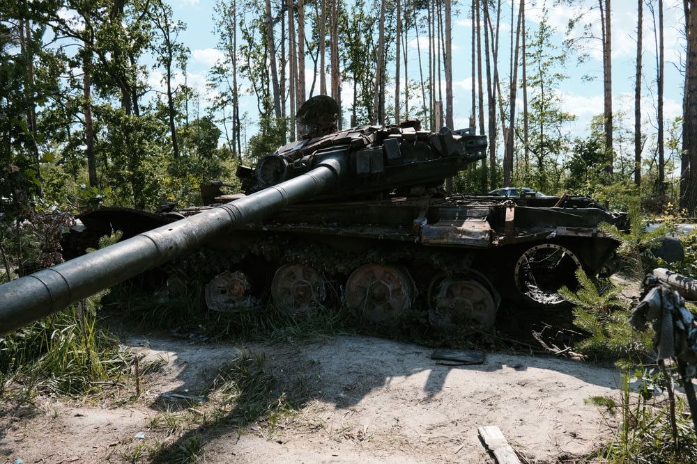 an old tank sitting in the middle of a forest