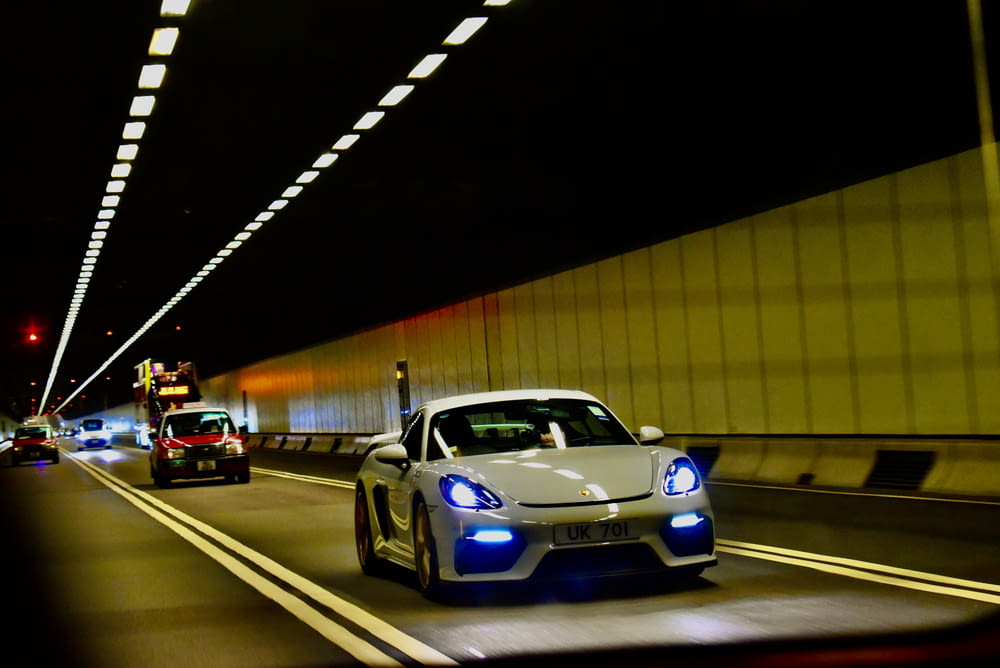 a white sports car driving down a highway at night