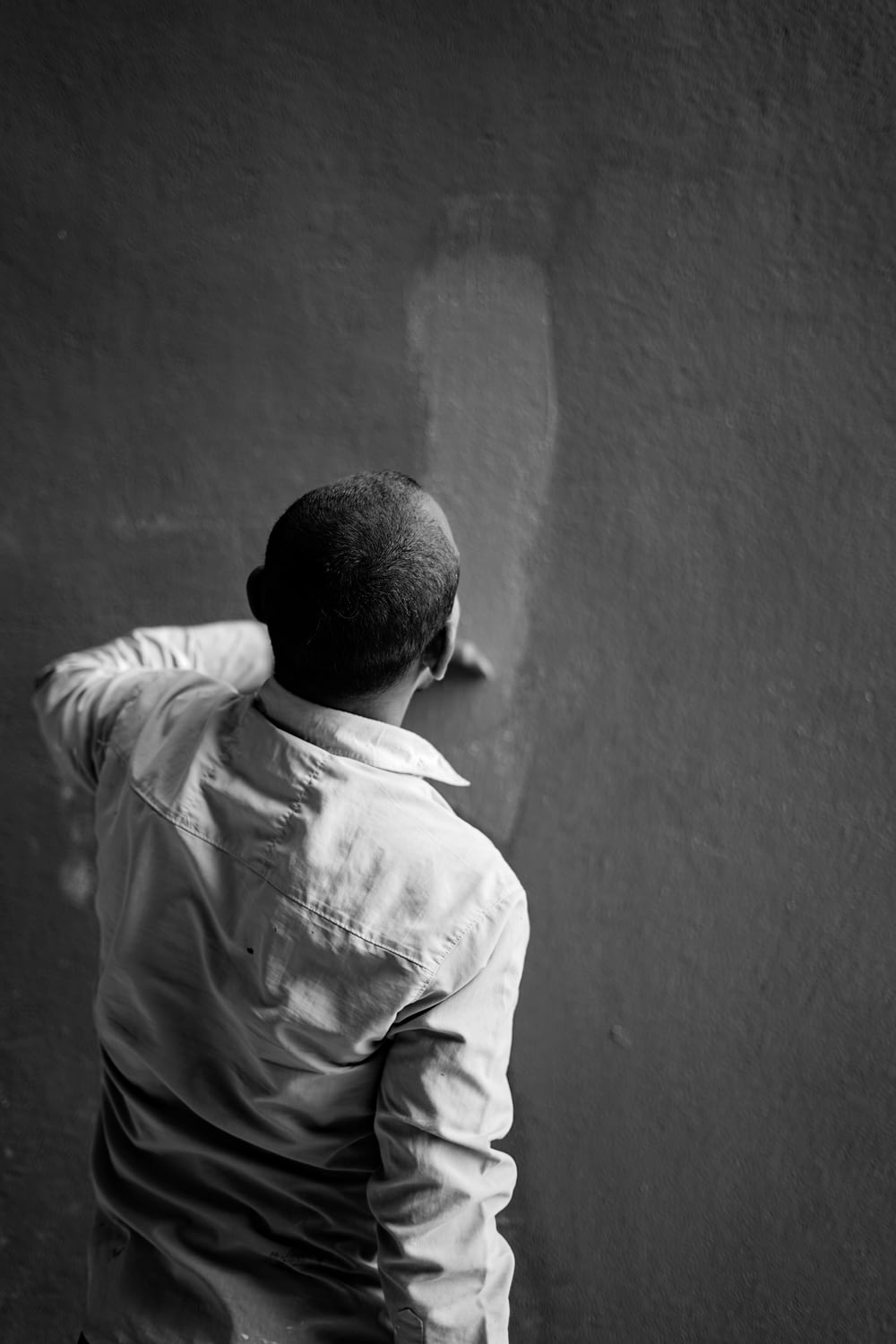 a man standing in front of a wall with his back to the camera