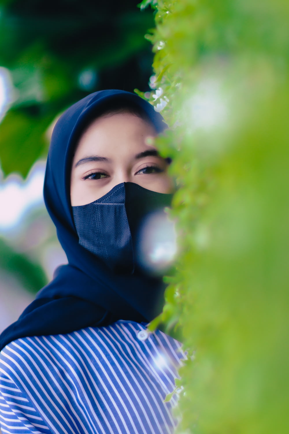 a woman wearing a blue hijab and a black mask