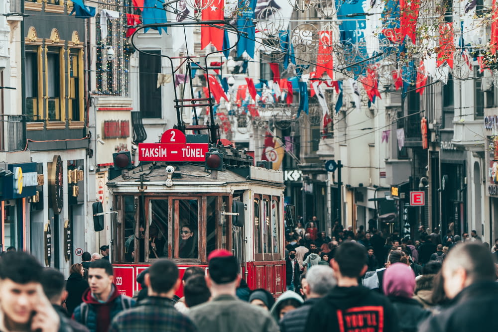 a crowd of people walking down a street next to a cable car