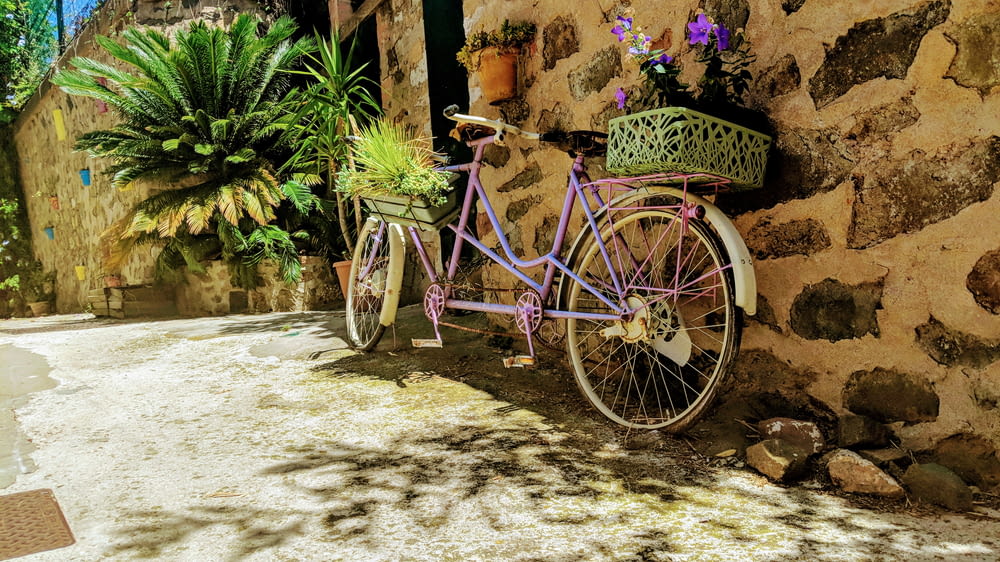 a purple bike parked next to a stone wall