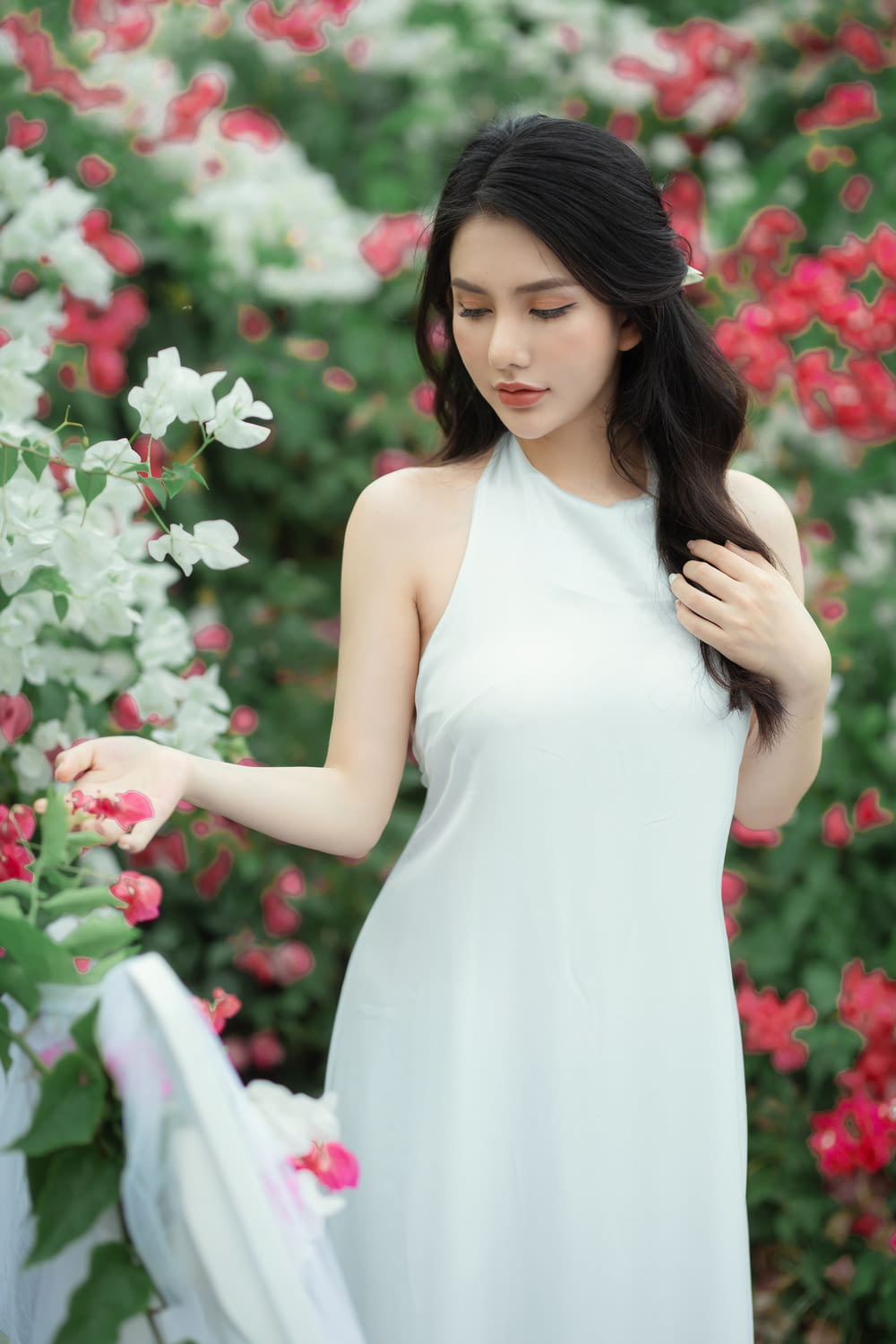 a woman in a white dress standing in front of flowers