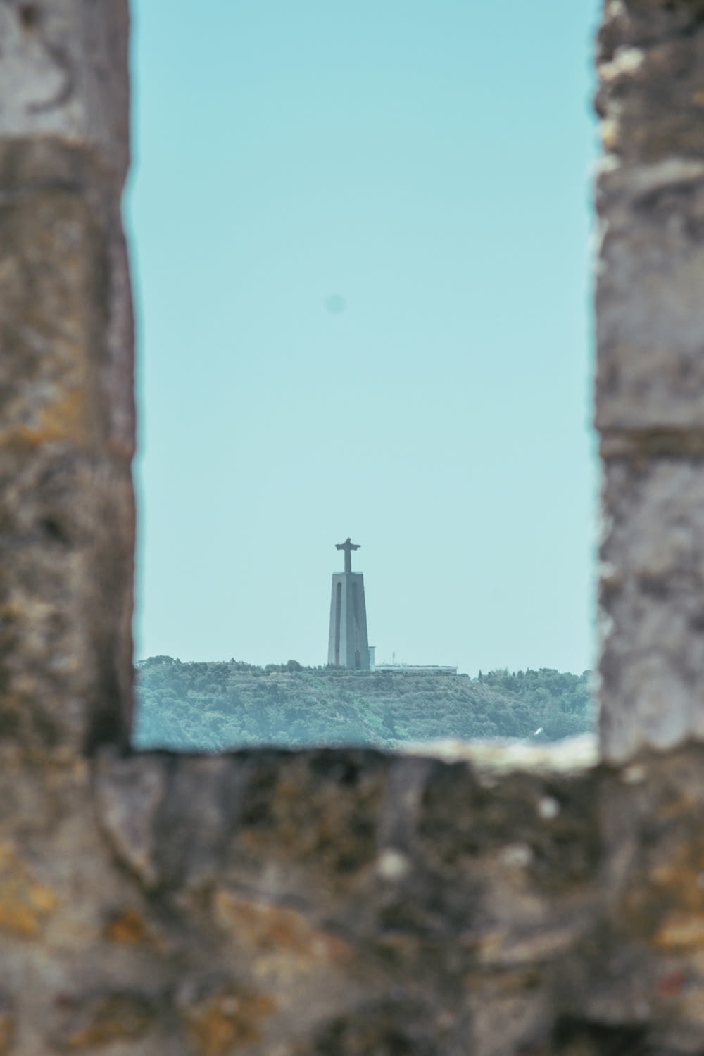 a view of a lighthouse through a hole in a stone wall
