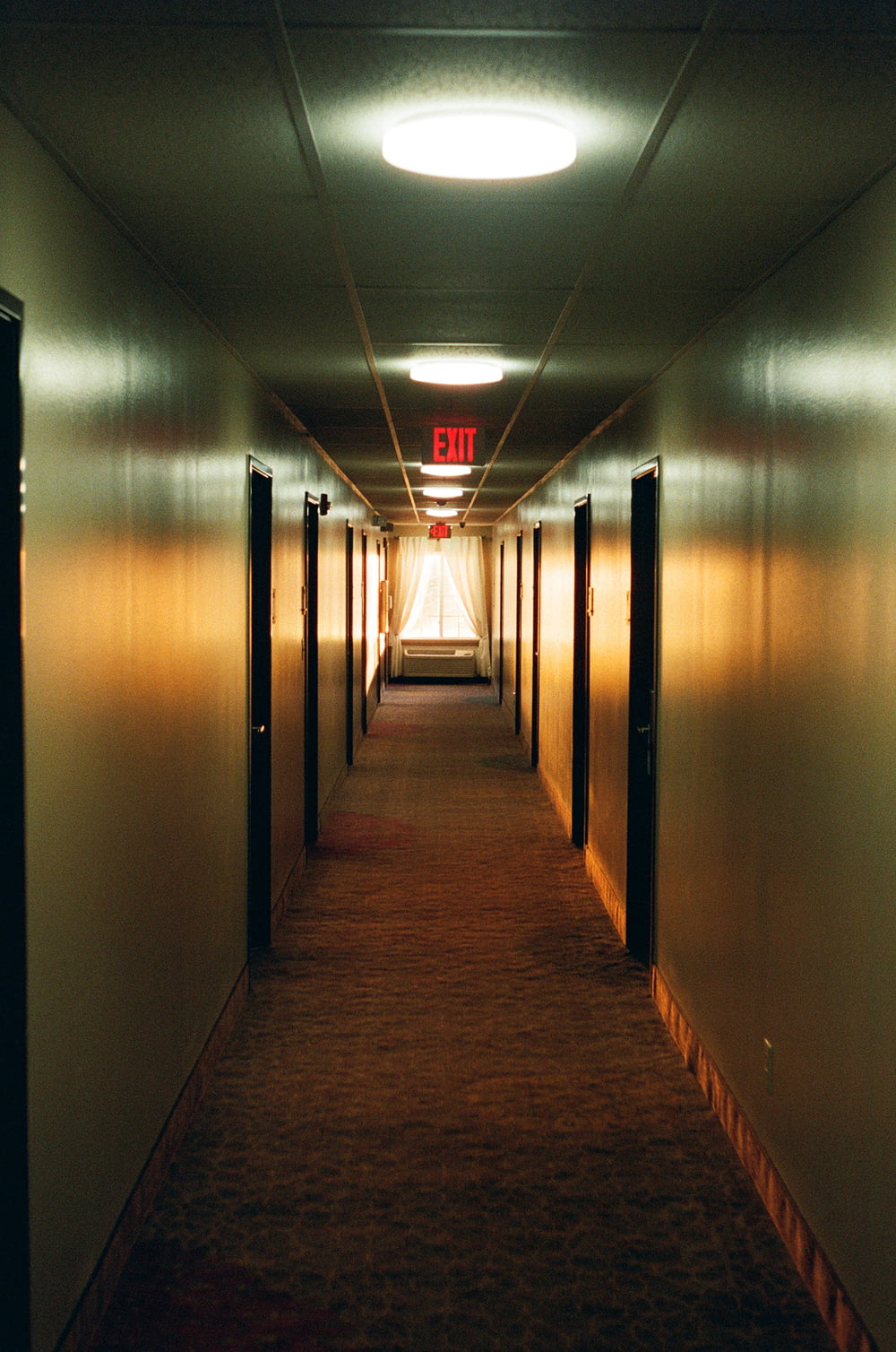 a long hallway with a exit sign on the wall