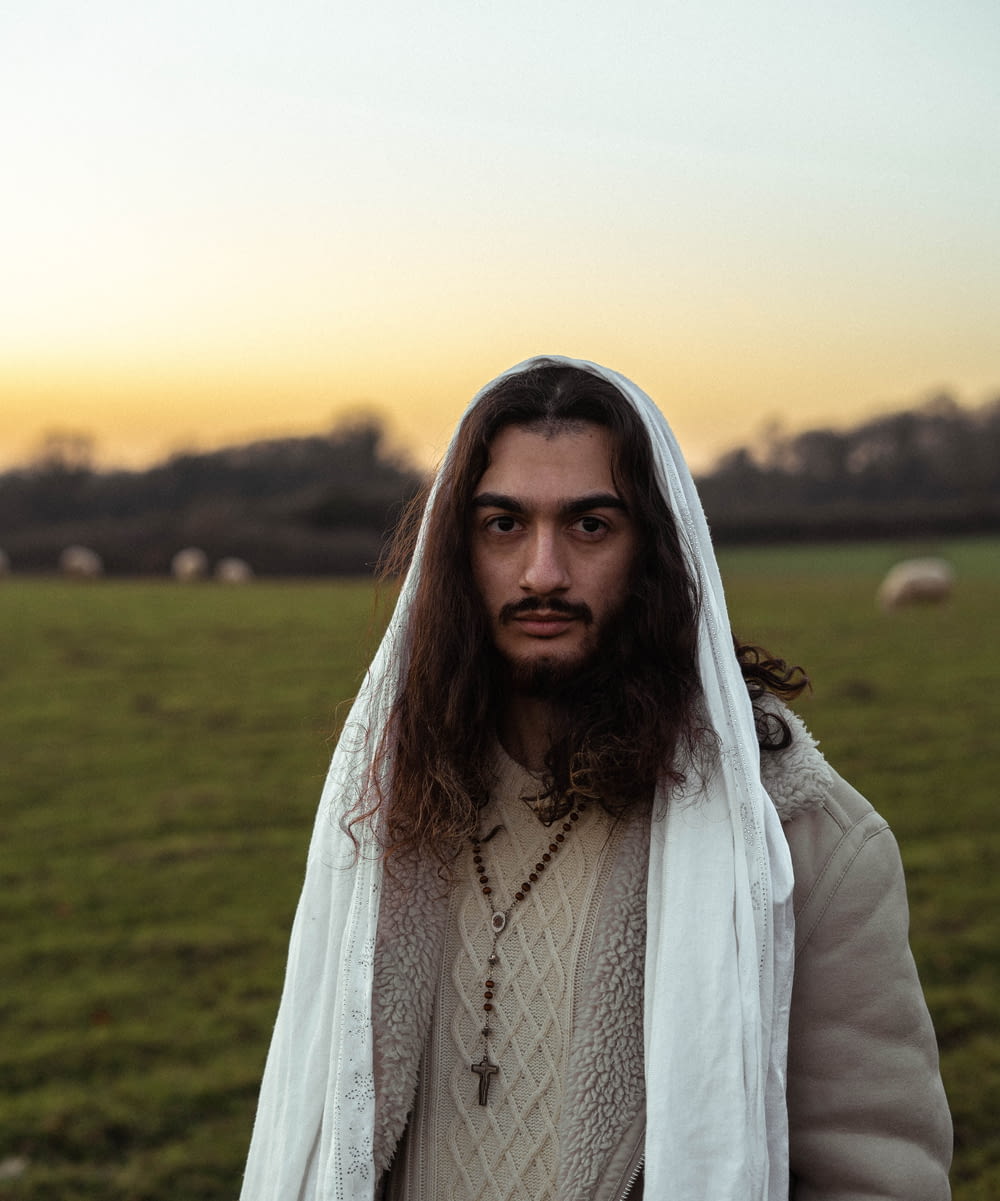 a man with long hair and a beard in a field