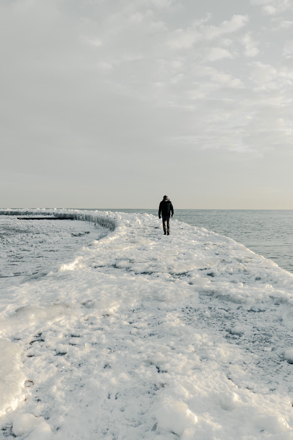 una persona che cammina lungo una linea costiera coperta di neve