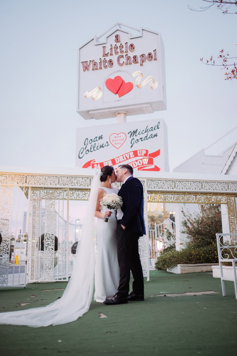 a bride and groom standing in front of a sign