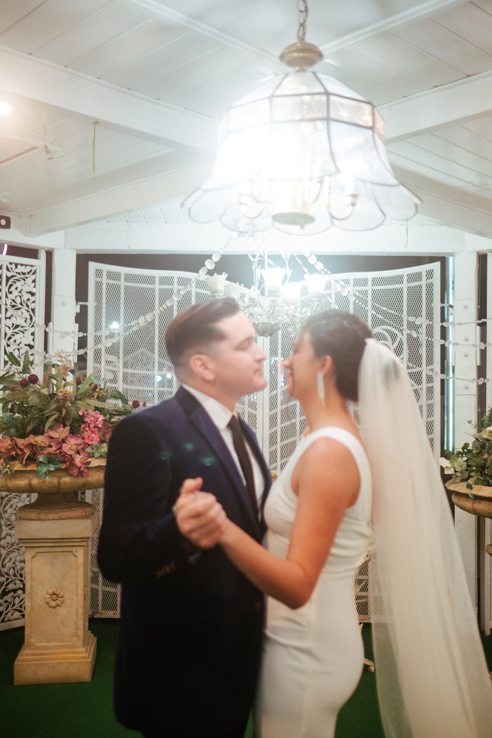 a bride and groom standing in front of a chandelier