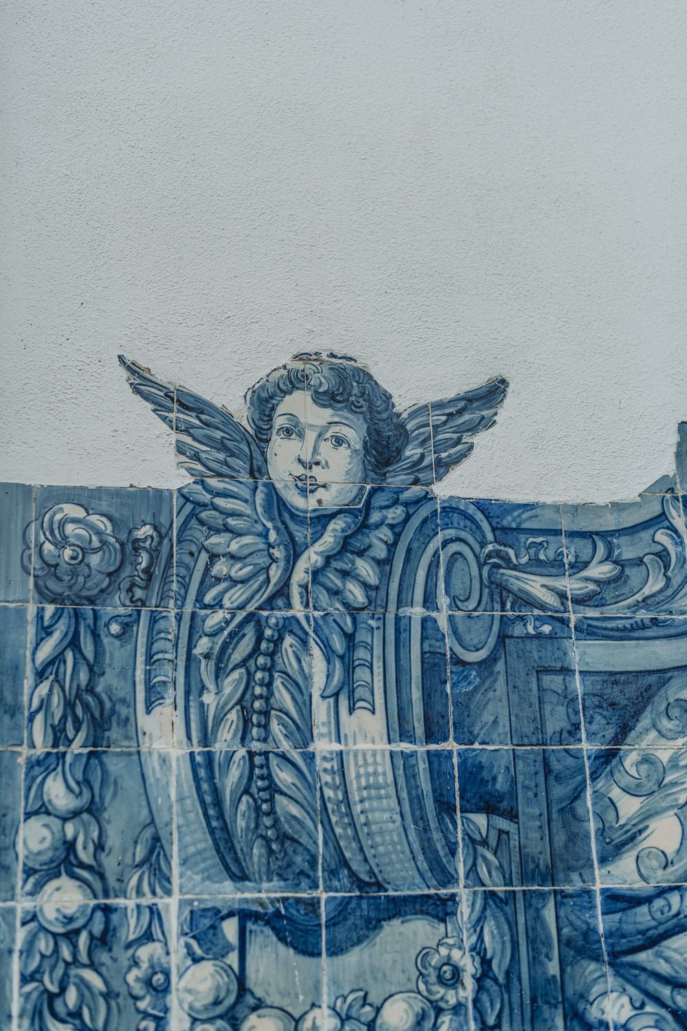 a blue and white tiled wall with an angel painted on it