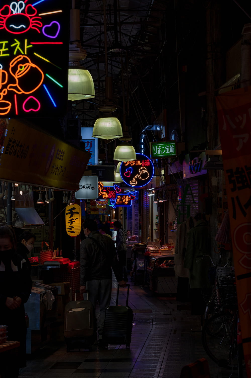 a dark alley with neon signs and people walking around