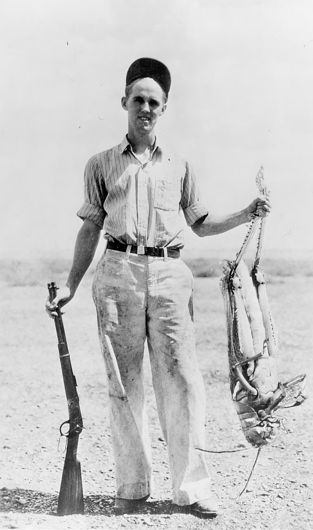 a man is holding a rifle and a fish
