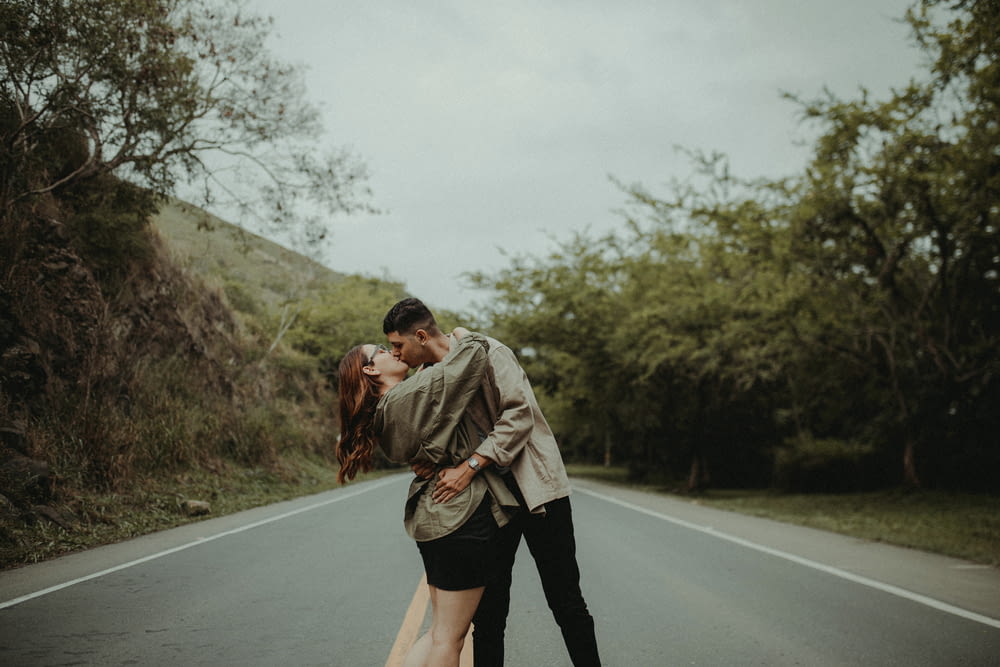 a man and woman kissing on the side of a road