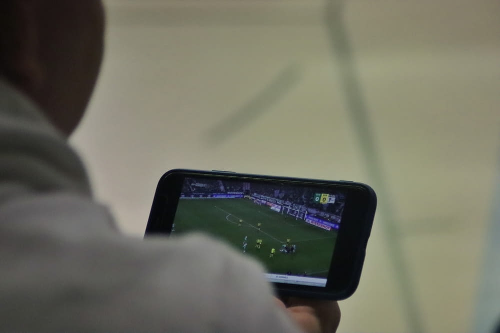 男が携帯電話でサッカーの試合をしている