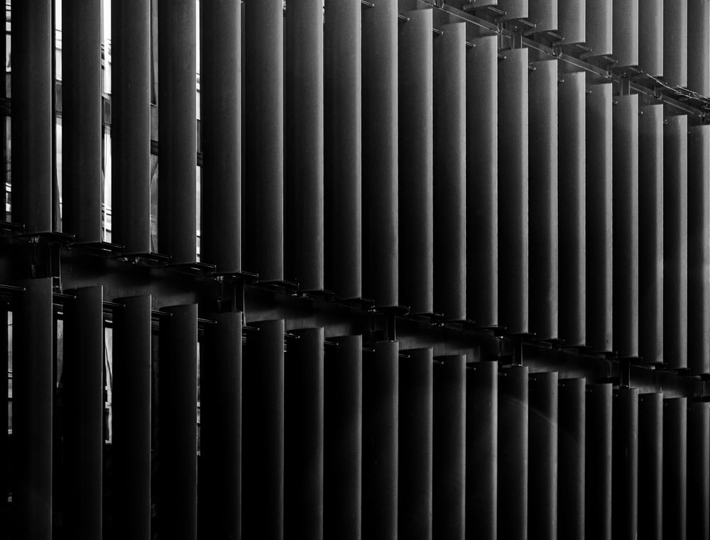 a black and white photo of a wall made of metal pipes
