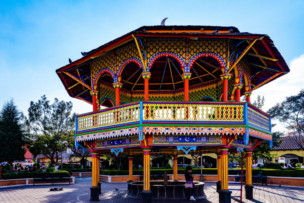 a colorful gazebo in a park with a blue sky in the background