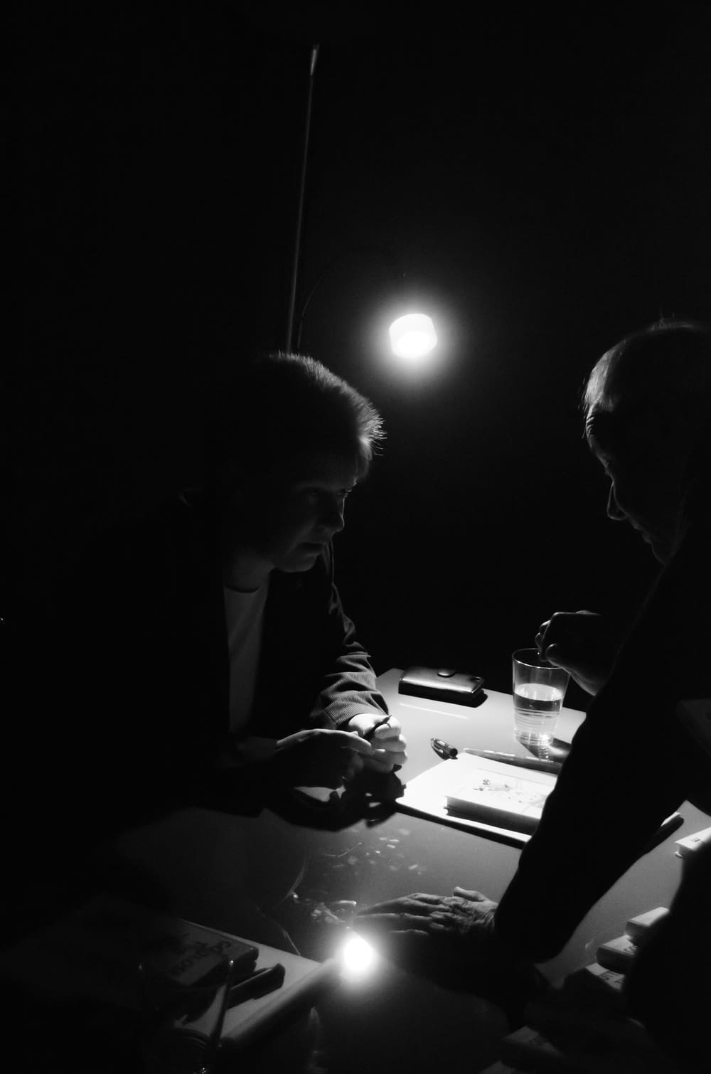 a couple of men sitting at a table in the dark