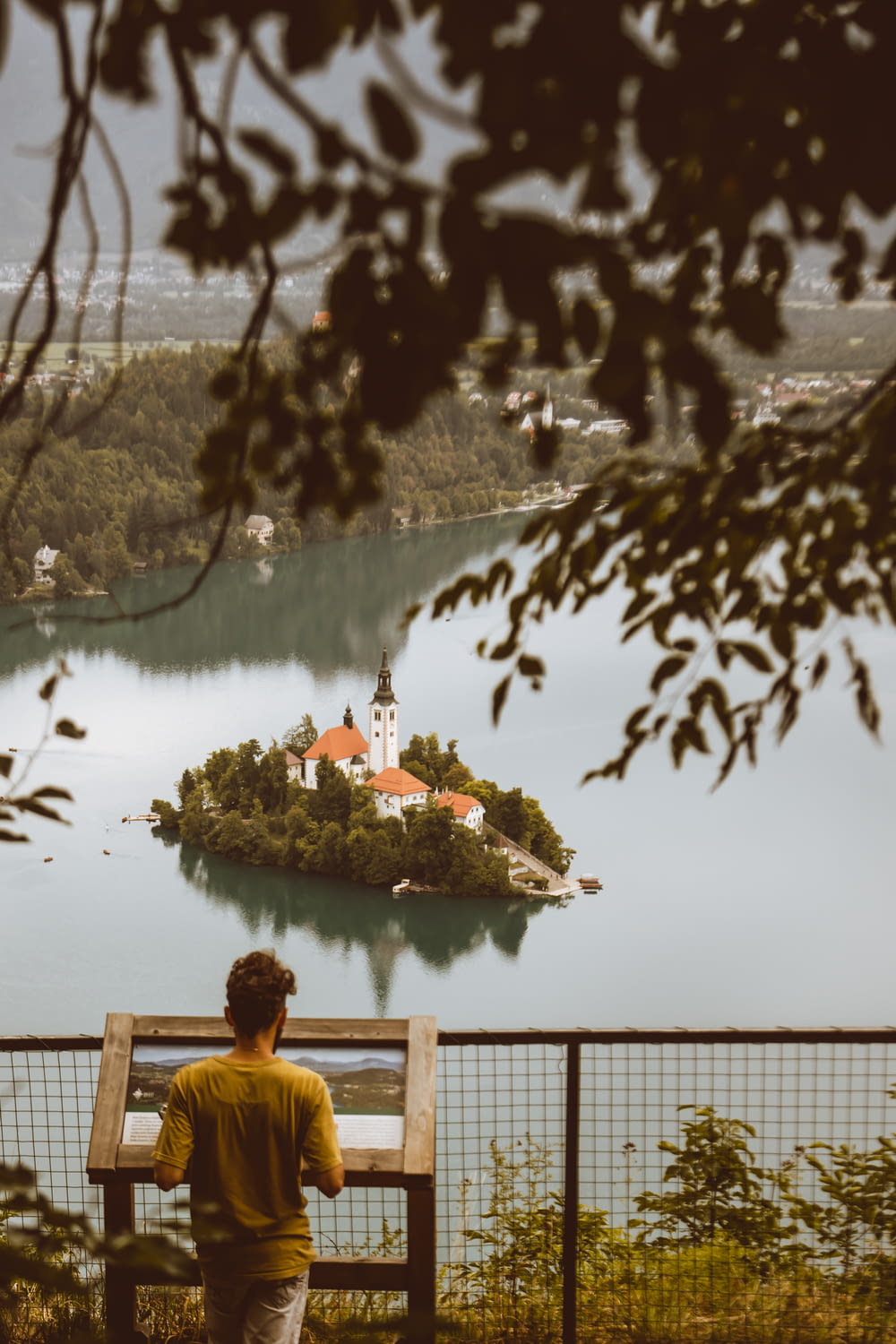a man sitting on a bench looking at a small island