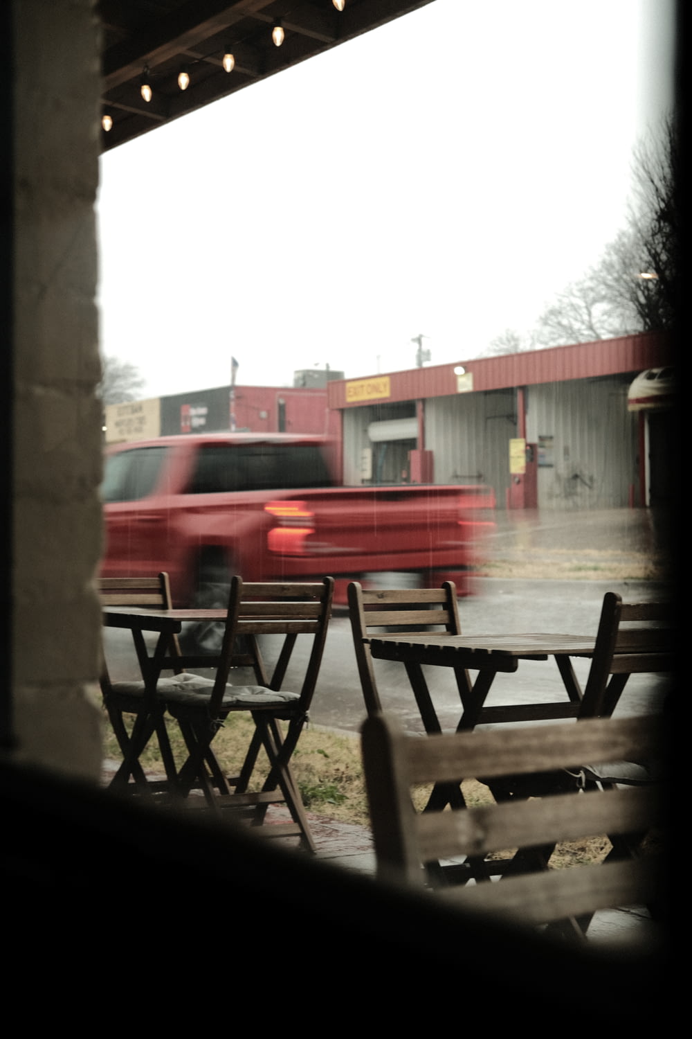 a red truck passing by a table and chairs
