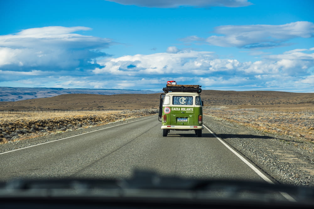 a green and white bus driving down a road