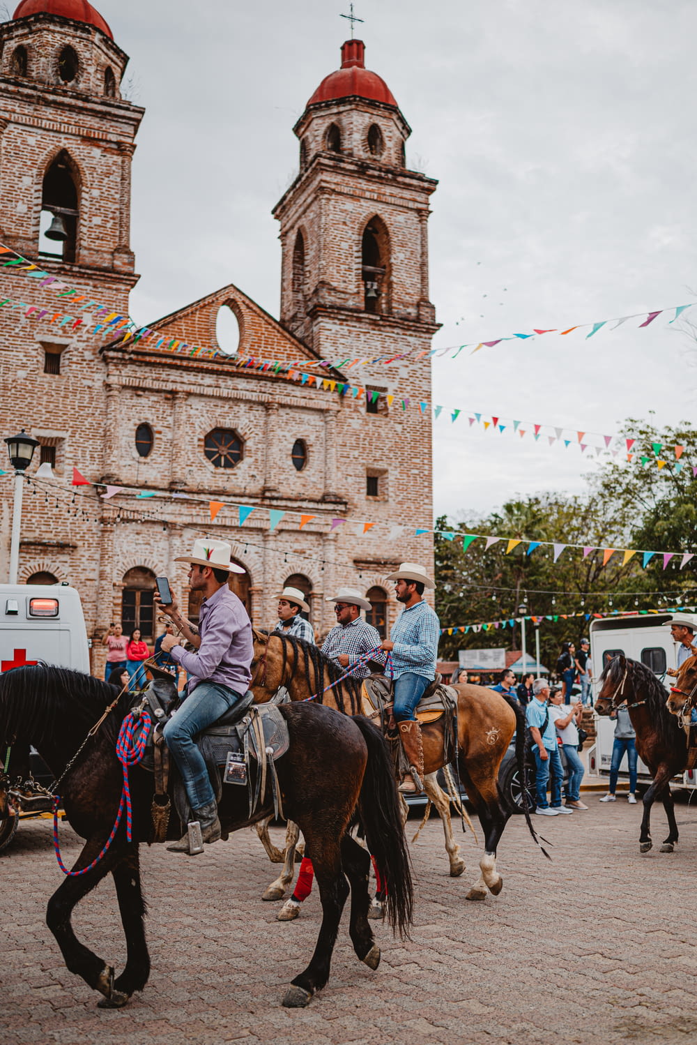 a group of people riding horses in front of a church
