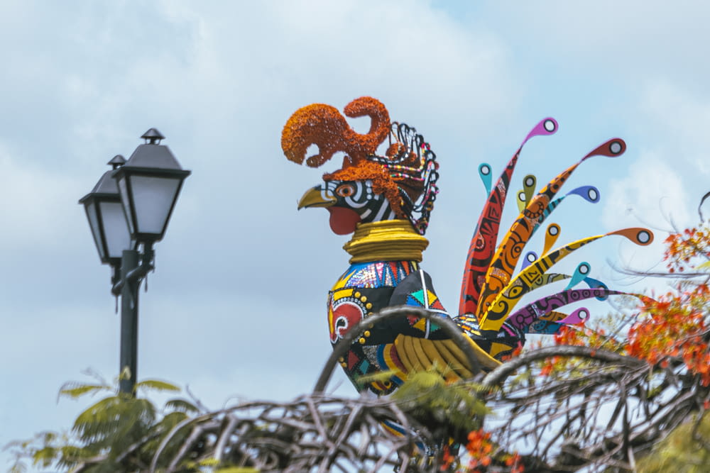 a colorful rooster statue next to a street light